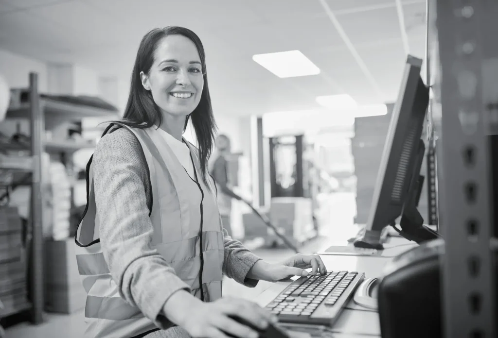 Smiling female logistics coordinator working at computer desk in office