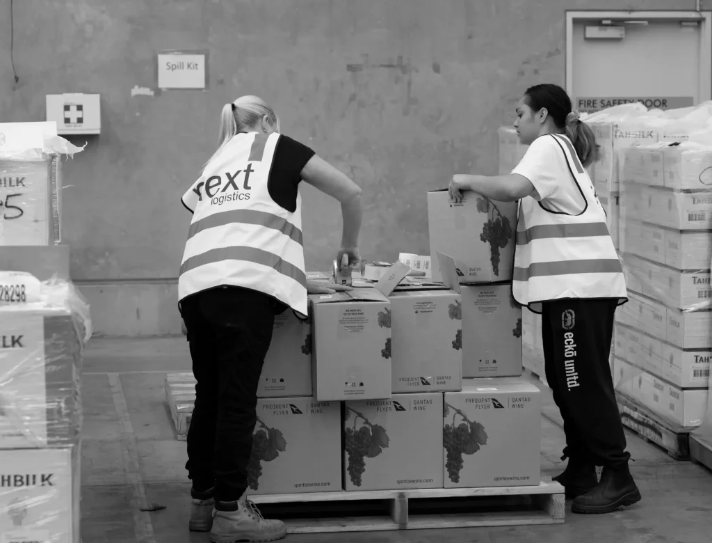 Two warehouse associates collaborating on multi-part component assembly